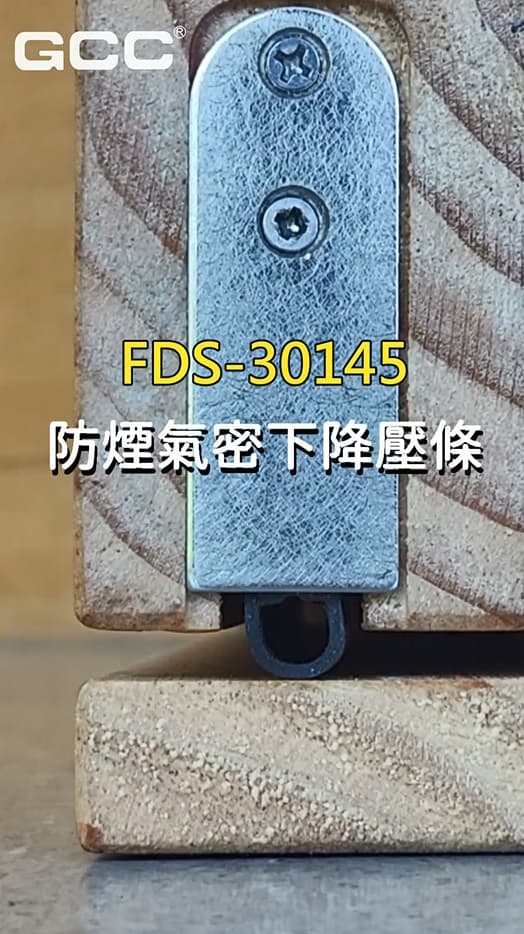 木门底部的FDS-30145防烟气密下降压条,展示金属板与黑色橡胶密封件。